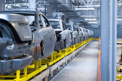 A line of cars being manufactured in an automotive facility