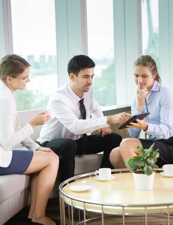 A small group of hospitality professionals sitting and gathering around a tablet