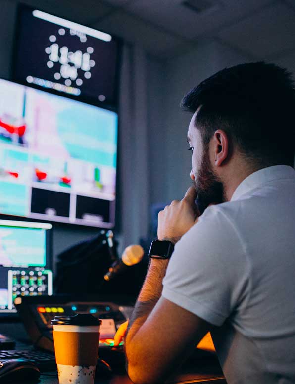 A man looking at various screens in a media studio