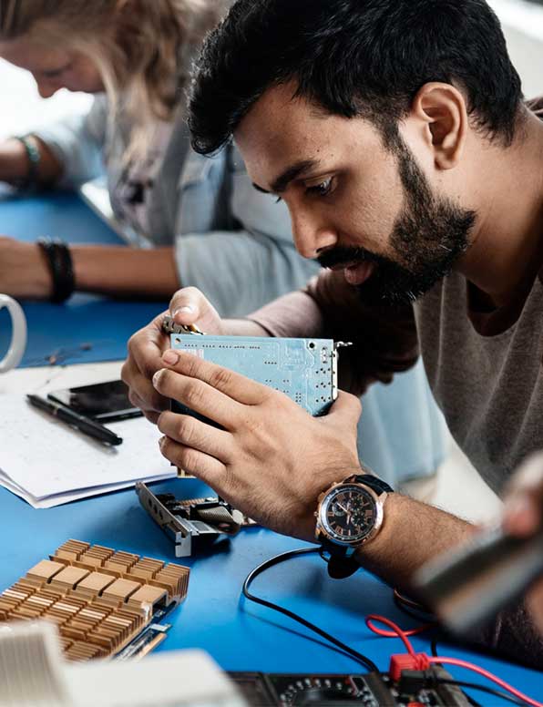 A man sitting and fixing a circuit board and electronics