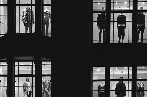 Black and white store windows with mannequins looking outward
